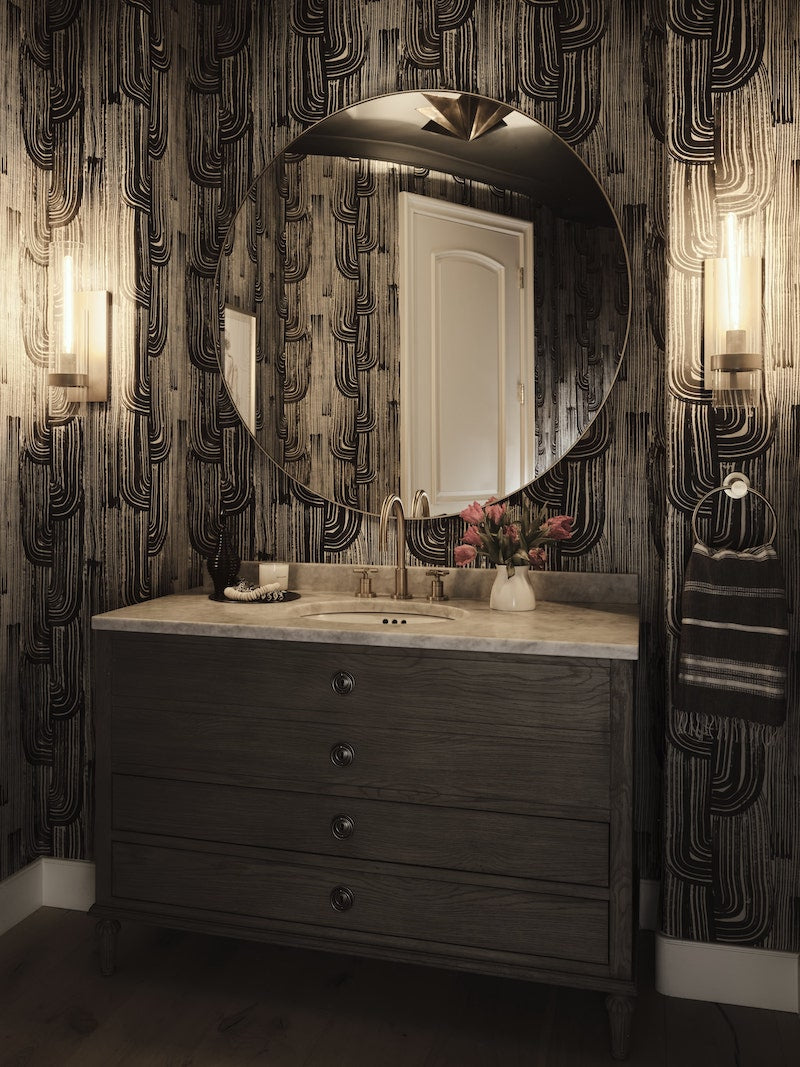 Bathroom With Dark Walls And A Large Round Mirror Above The Sink